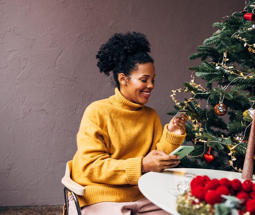 Woman looking at her phone to learn more about holiday scams.