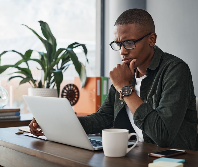 A man sits at a table looking at his laptop and wonders if he’s accidentally pirating software.