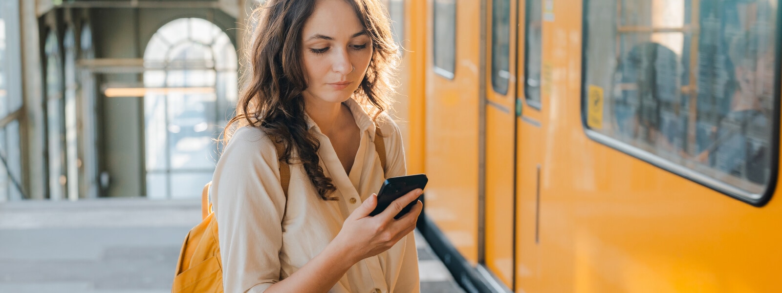 Woman is on a street near a stopped trolly looking at her phone learning about brute force attacks.