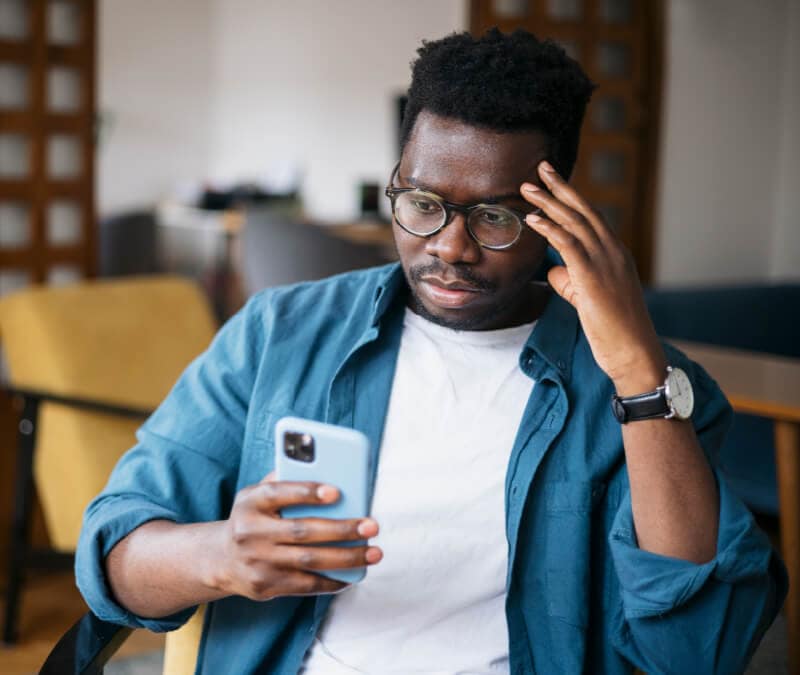 A man looking at his phone wondering “can iPhones get hacked?”