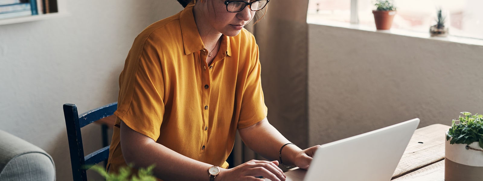 A person in a yellow shirt using a laptop computer to learn how to check if a website is safe.