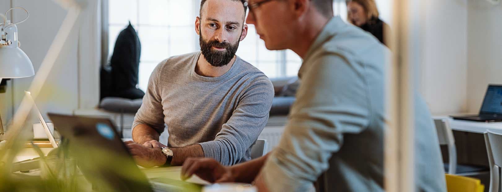 Two men sit at a computer reviewing the cryptography algorithm they want to use for their new secure messaging app.