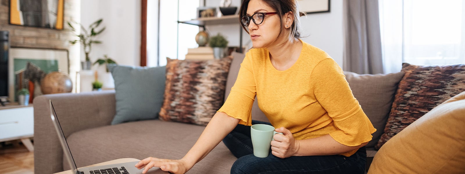 A person drinks coffee while they learn about cryptojacking on their computer.