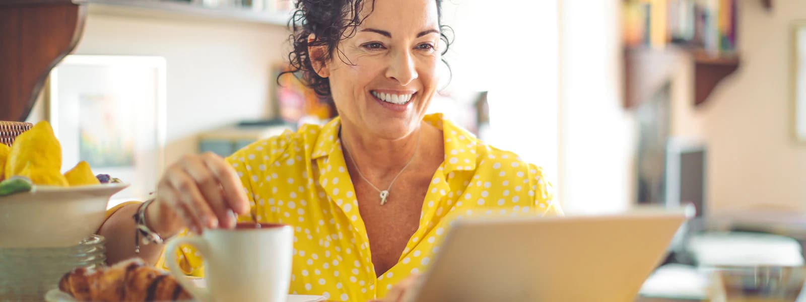 A woman enjoying coffee and browsing cybersecurity trends on her laptop.