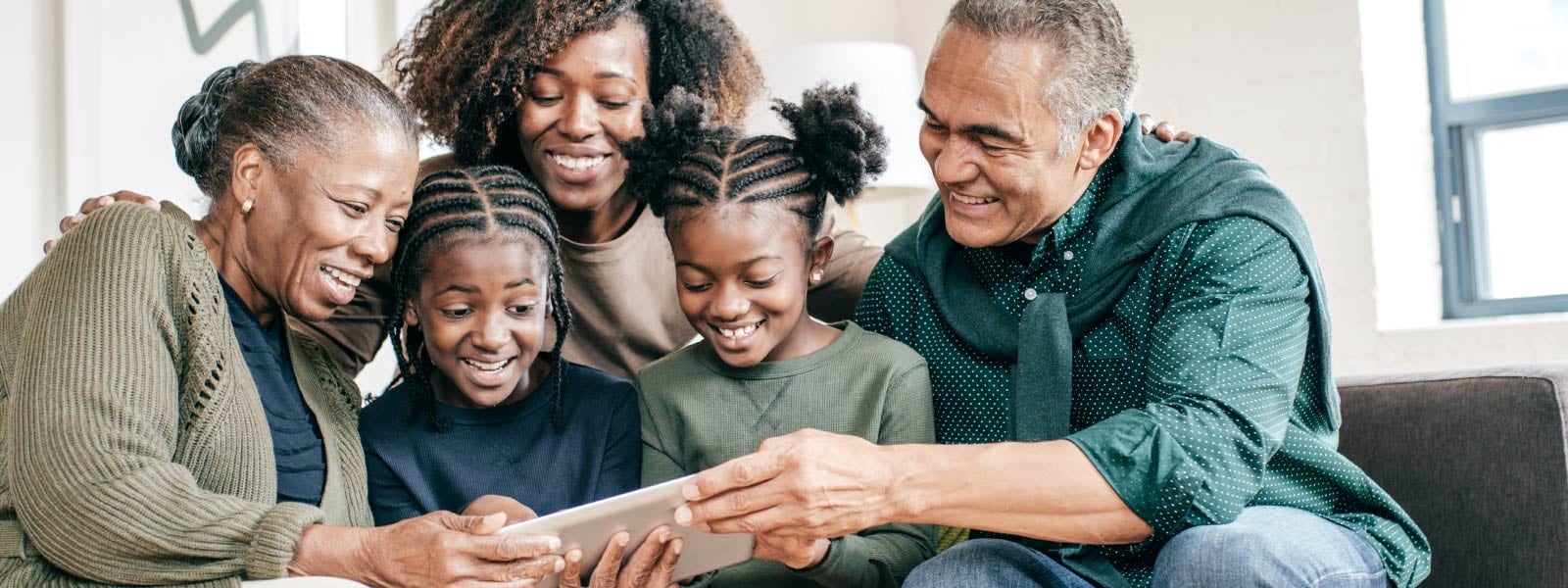 A family gathered on a couch, engrossed in a tablet.