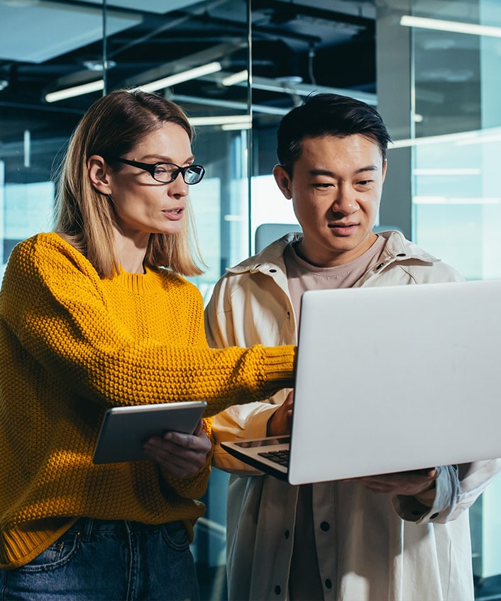 A man and a woman check to see if their firewall is enabled on their laptop.