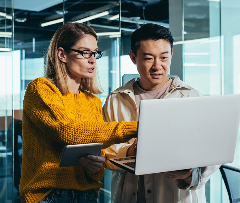 A man and a woman check to see if their firewall is enabled on their laptop.