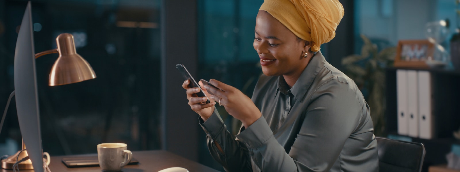 Woman at a desk using her smartphone after learning how to choose antivirus software.