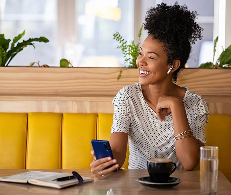 An individual on their iPhone in a cafe after learning how to use a VPN on an iPhone to stay safe.