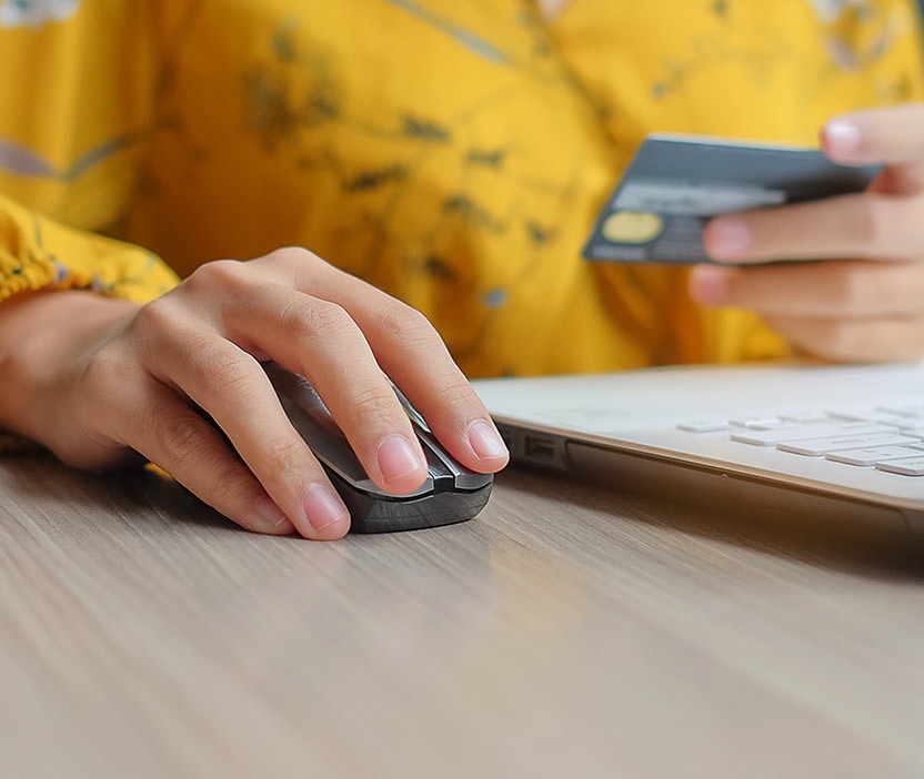 A person's hand holding a credit card and on a laptop, protecting themself from mobile security threats.