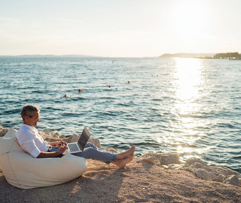 A man sitting on a beach, contemplating the risks of rooting his Android phone.