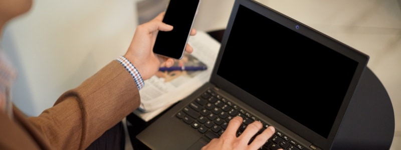 Person holding device about to research difference between black, white, and grey hat hackers