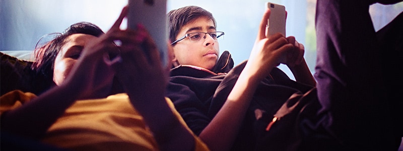 Two children looking intensely at their mobile devices.