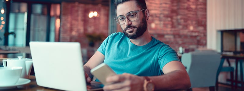 A man using a laptop and mobile device to protect himself from malvertising threats.