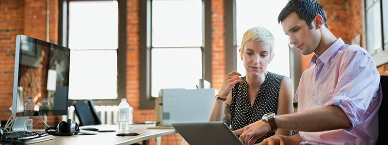 A man and woman working together on a laptop, discussing the potential of the Internet of Things.