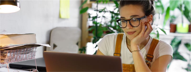 A woman in glasses gazes at a laptop, potentially avoid a rootkit attack.