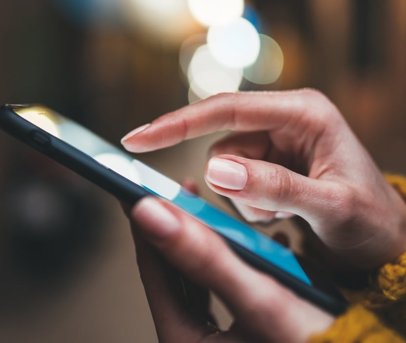 Close up of a woman's hands holding a smartphone, looking for Taylor Swift deepfakes.