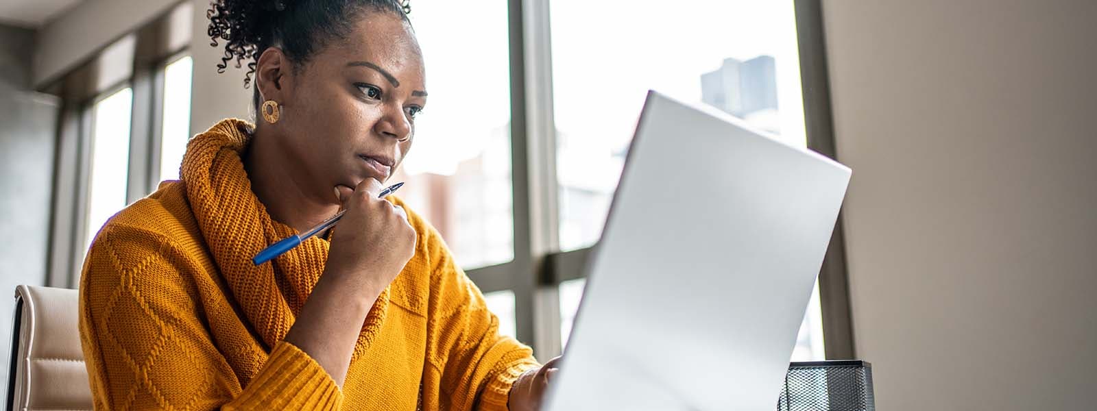 A business executive looks at her computer and considers next steps after a whaling attack. 