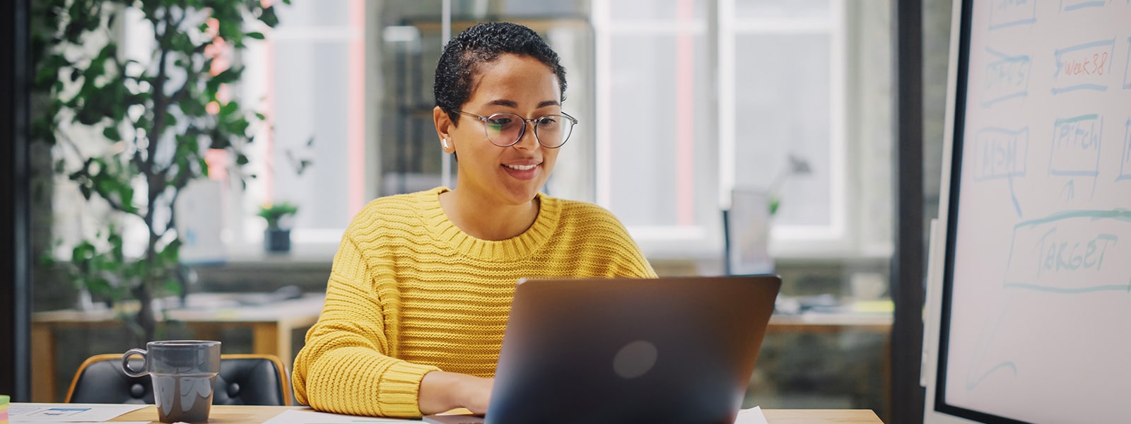 A person in a yellow sweater looking up the answer to what is antivirus on a laptop.