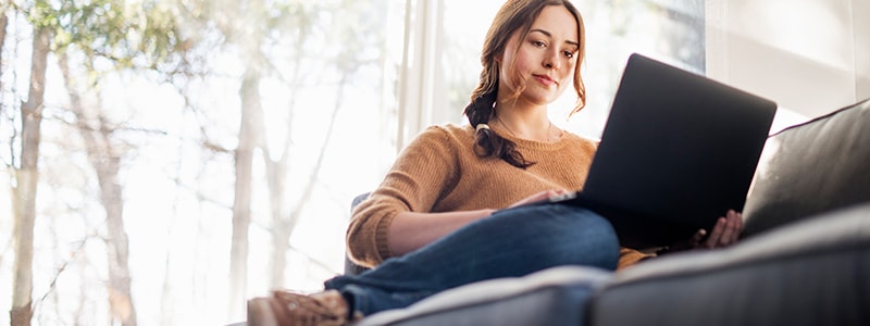 A person on a couch researching how to protect their online privacy.