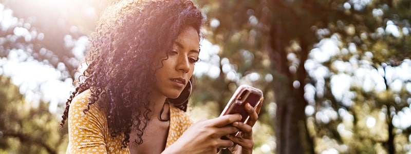 A woman using her mobile phone to block spam emails with Norton security software.