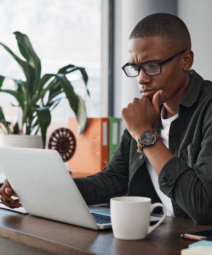 A man sits at a table looking at his laptop and wonders if he’s accidentally pirating software.