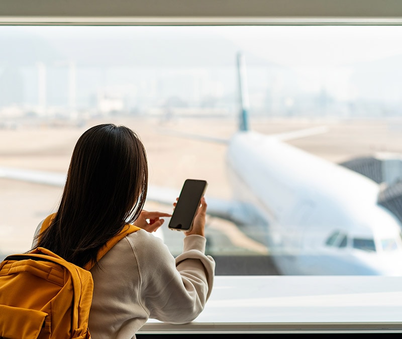 A photograph of a woman using a VPN to safely access airport public Wi-Fi. 