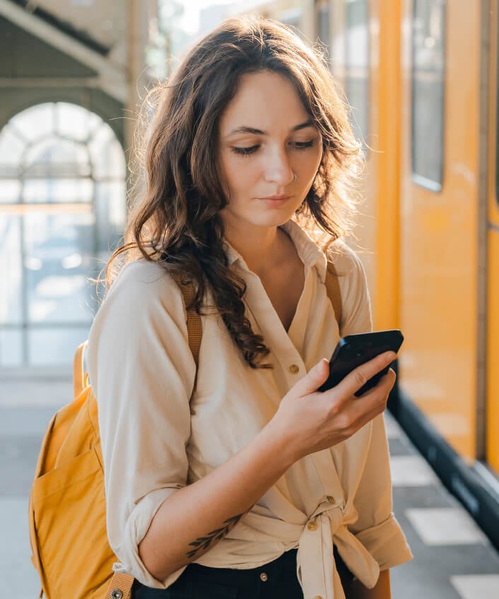 Woman is on a street near a stopped trolly looking at her phone learning about brute force attacks.