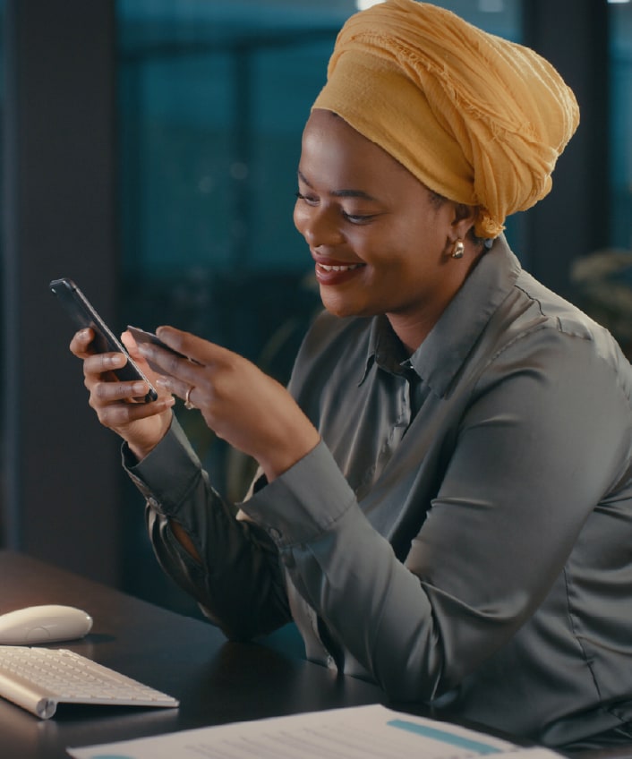 Woman at a desk using her smartphone after learning how to choose antivirus software.