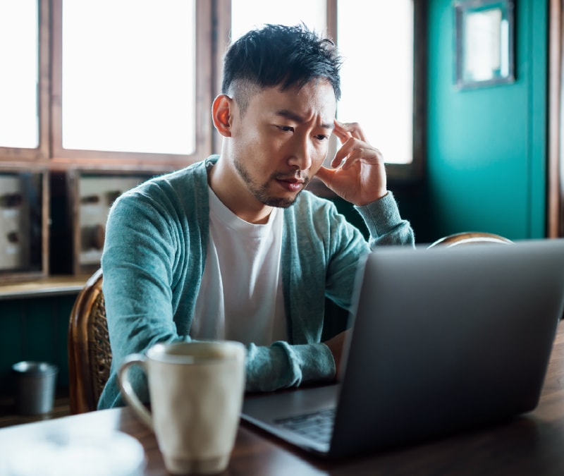 A man looking up how to report a website for scamming on a laptop.