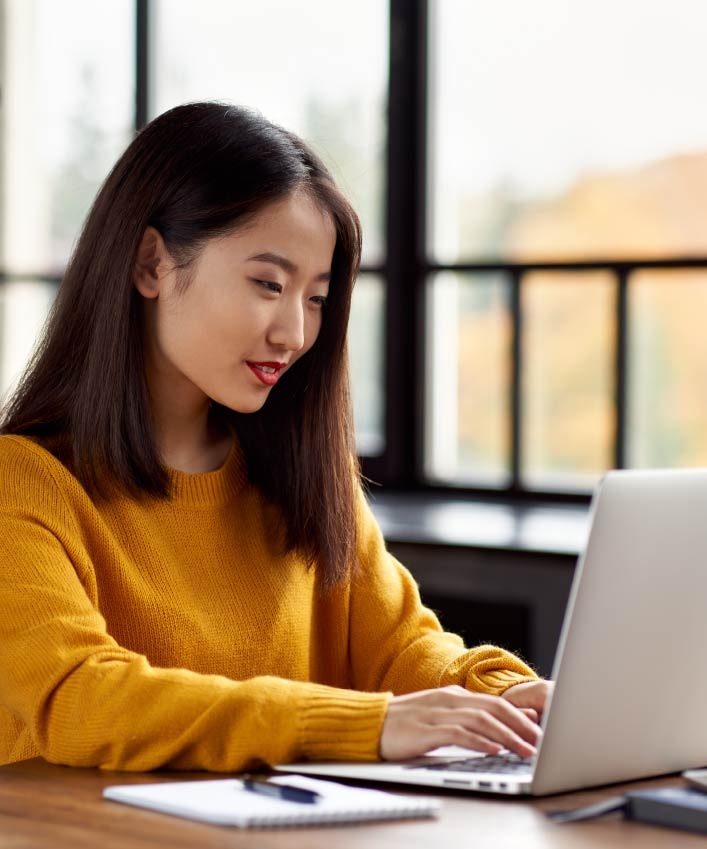 A woman using a laptop in order to look up how to send an anonymous email.