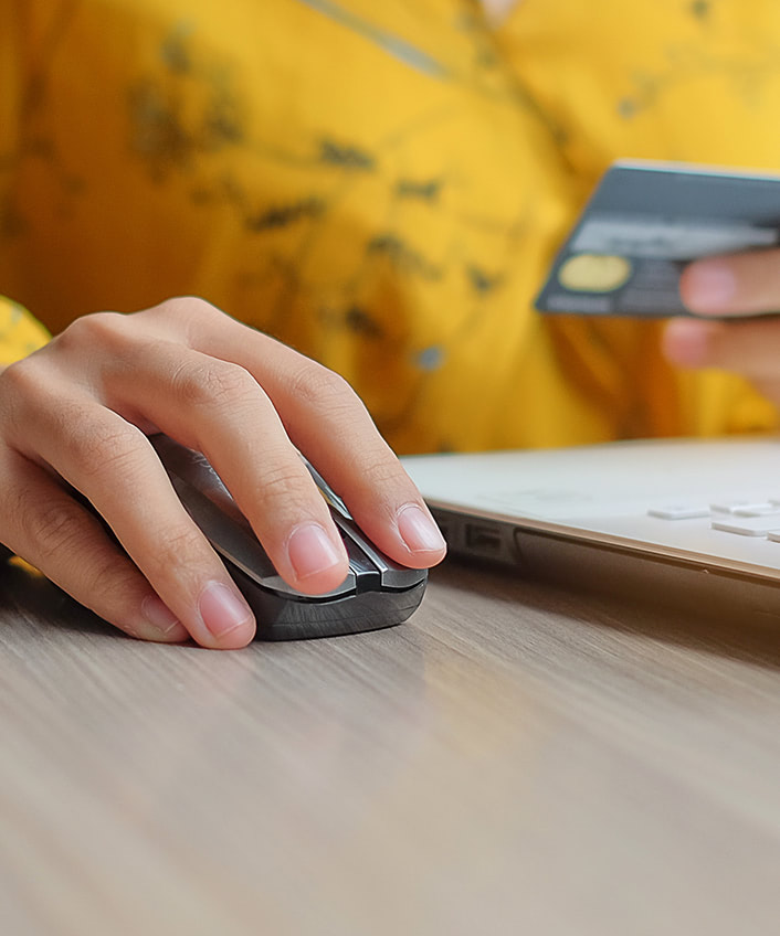 A person's hand holding a credit card and on a laptop, protecting themself from mobile security threats.