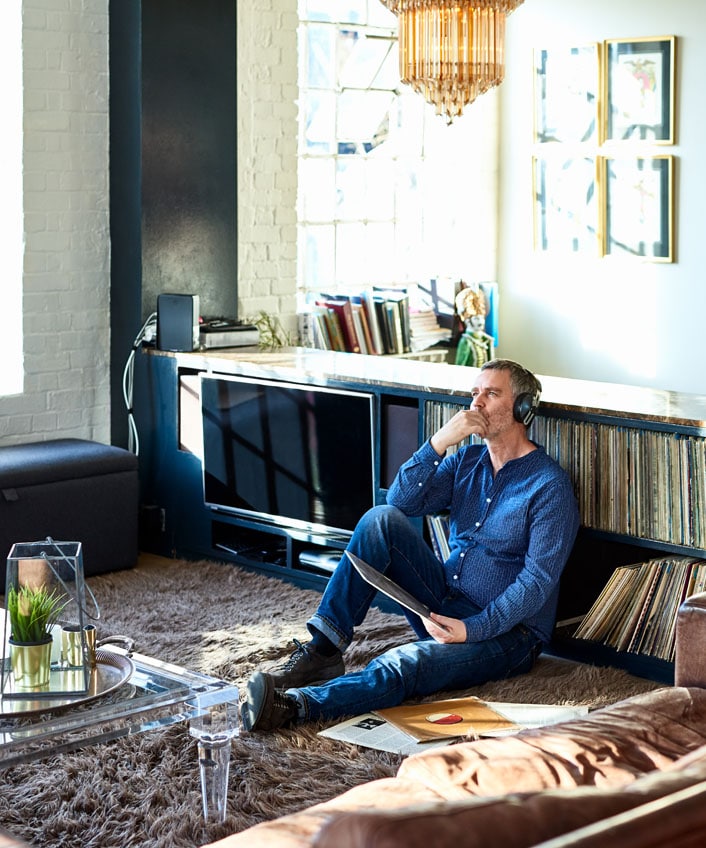 A man listening to music with headphones while extending Wi-Fi range.