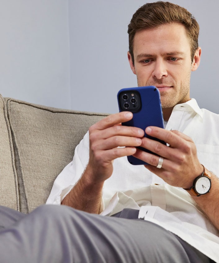 A man holding a blue phone, looking for a solution to unlock his blocked Facebook account.