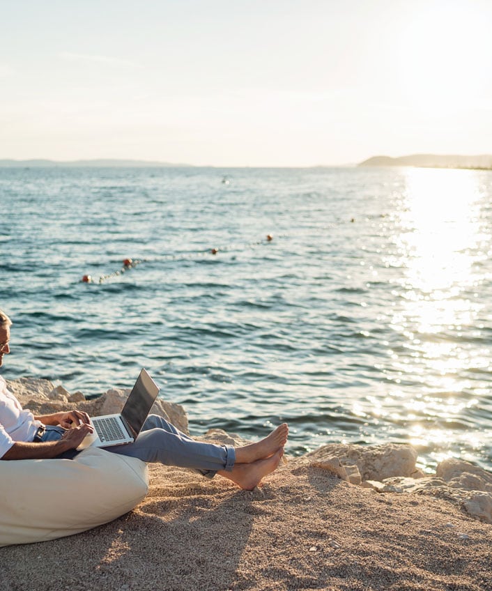 A man sitting on a beach, contemplating the risks of rooting his Android phone.