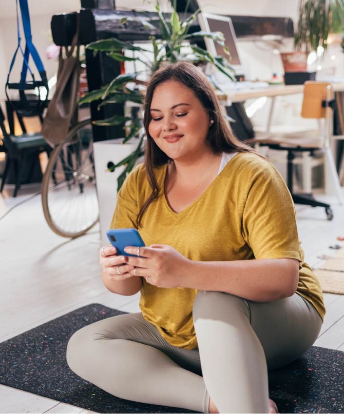 A woman uses her phone to check her bank accounts and wonders, "is mobile banking safe?"