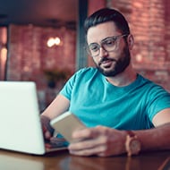 A man using a laptop and mobile device to protect himself from malvertising threats.