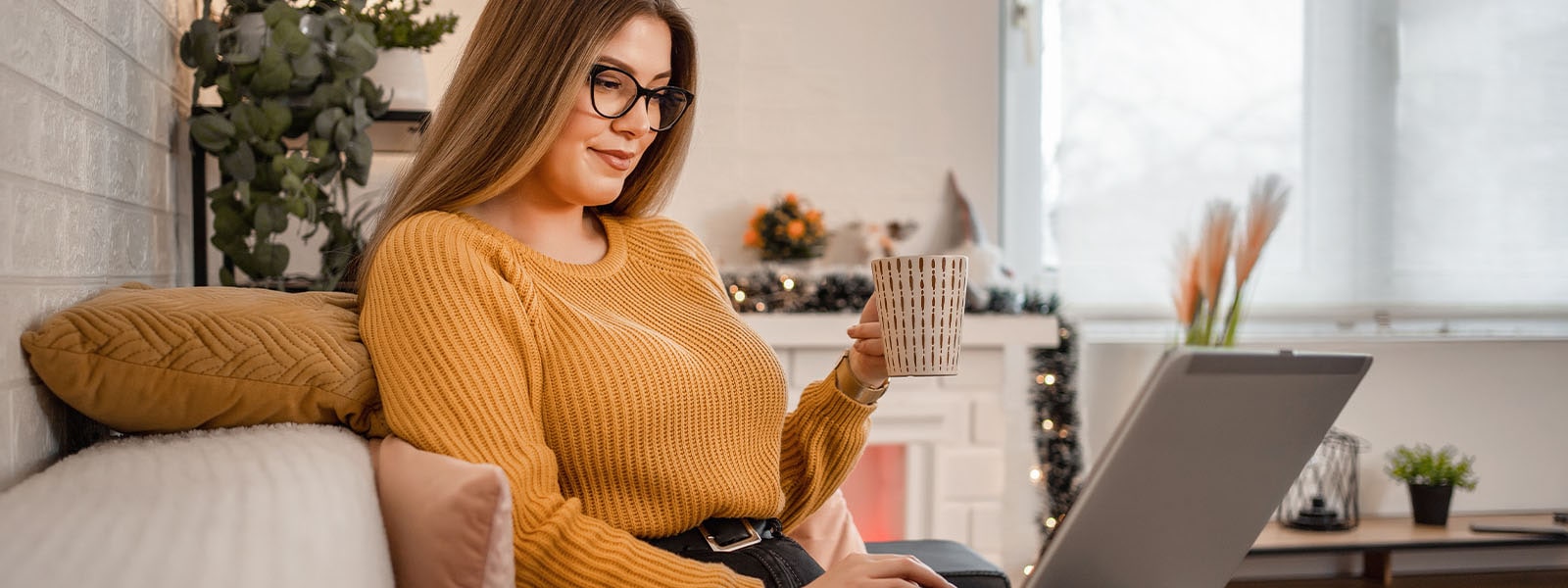 A woman sits on the couch and reads about pass the hash attacks on her computer.