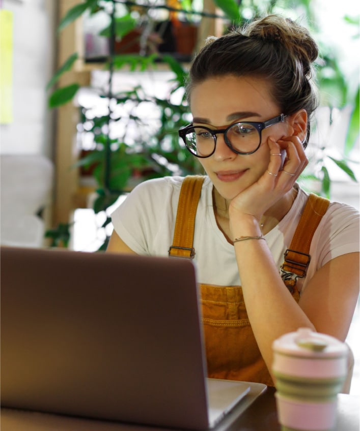 A woman in glasses gazes at a laptop, potentially avoid a rootkit attack.