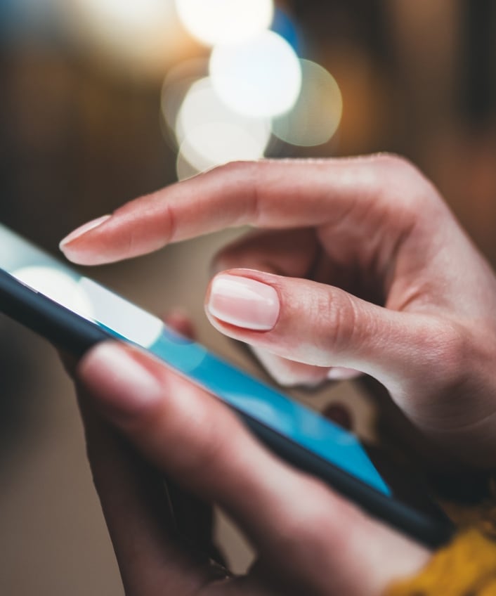 Close up of a woman's hands holding a smartphone, looking for Taylor Swift deepfakes.