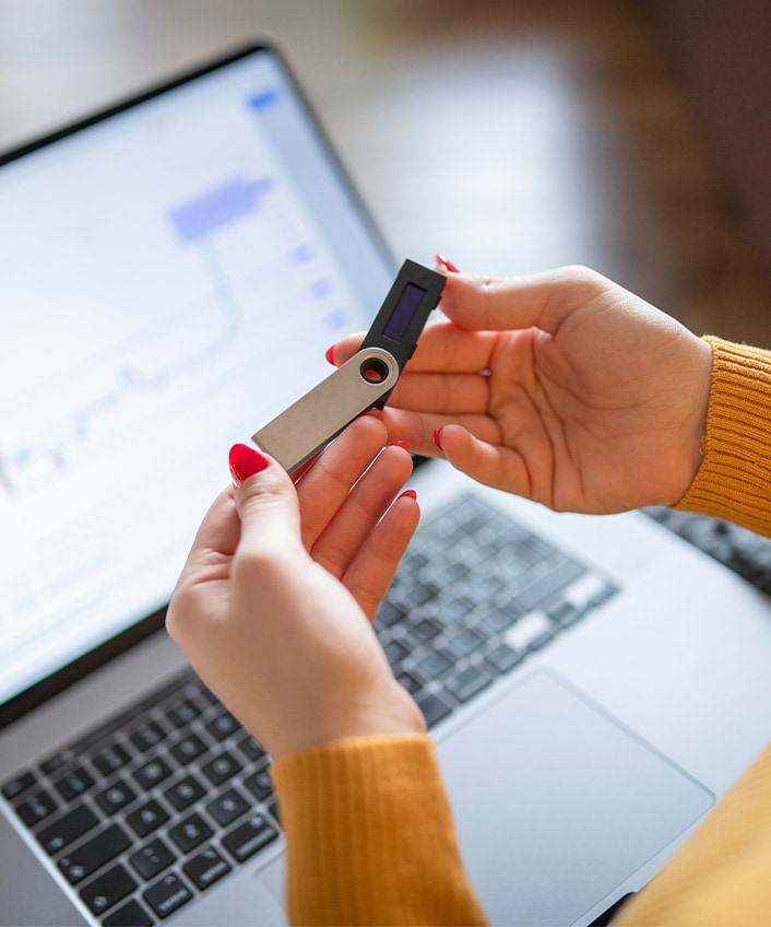 A woman opens a flash drive before plugging it into a laptop.