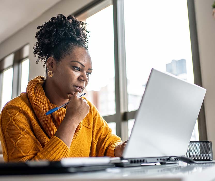 A business executive looks at her computer and considers next steps after a whaling attack. 