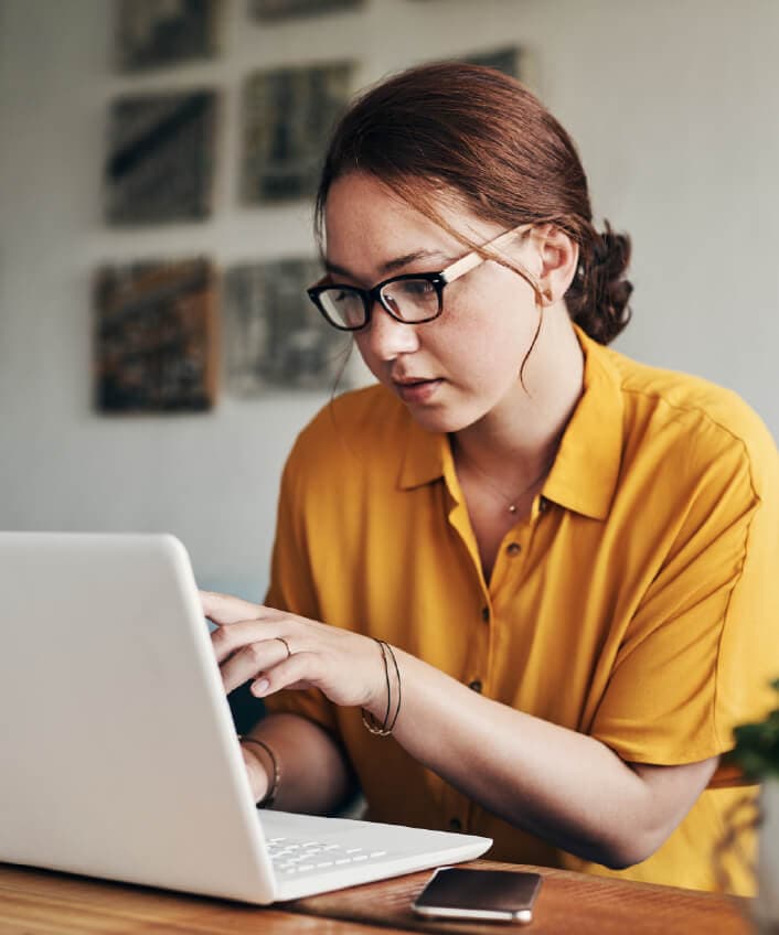 Woman looking at laptop learning about watering hole attacks.