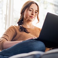 A person on a couch researching how to protect their online privacy.