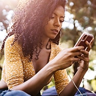 A woman using her mobile phone to block spam emails with Norton security software.